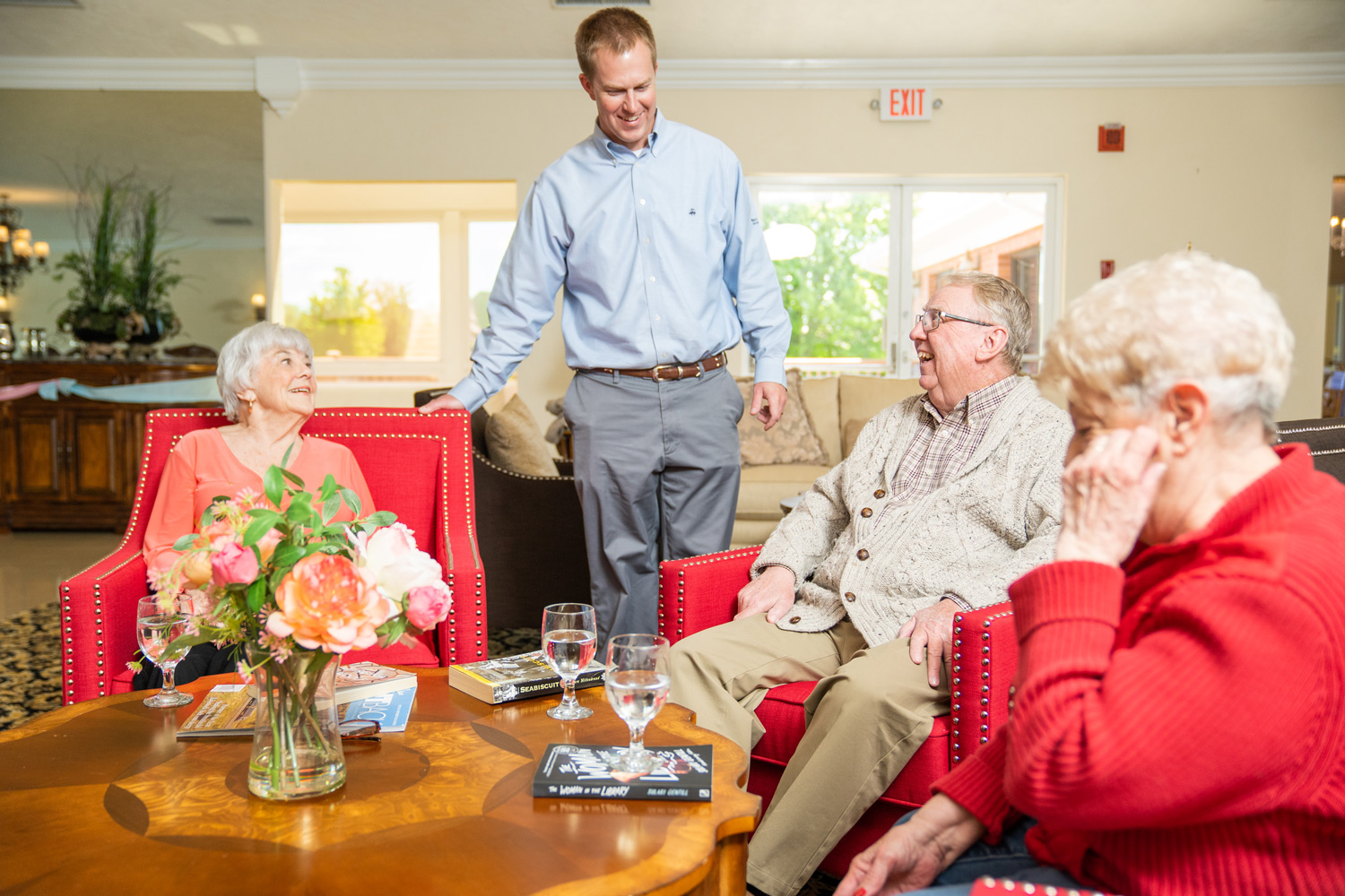 Residents and a staff member at Mari De Villa enjoying a social gathering in a comfortable lounge setting.